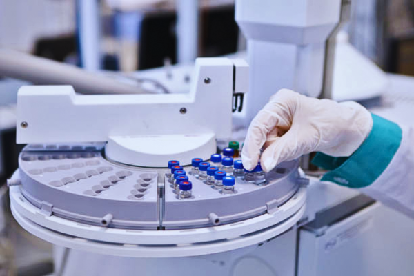 A woman operates a gas chromatograph in a pharmaceutical lab, using advanced lab instruments for DNA analysis. These tools are essential in quality control and the development of COVID-19 vaccines.