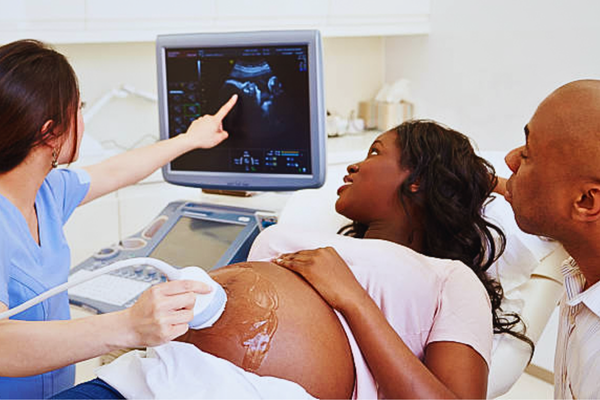 Expectant couple watching a 4D ultrasound scan while discussing prenatal DNA screening for early insights into their baby's health