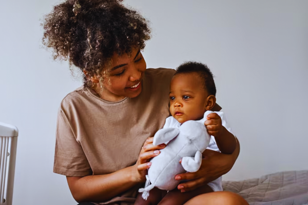 Smiling mother gently holding her baby, representing the emotional journey and awareness surrounding Down syndrome pregnancy symptoms during prenatal care