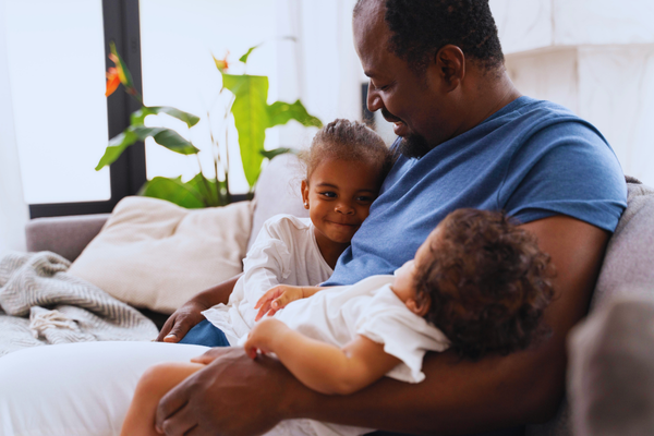 Man holding his daughters in his arms, symbolizing family bonds while highlighting emotional and legal concerns related to misattributed paternity.