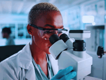 Female scientist using a microscope in a laboratory during test analysis and medical research, illustrating advanced procedures involved in genetic health screening.