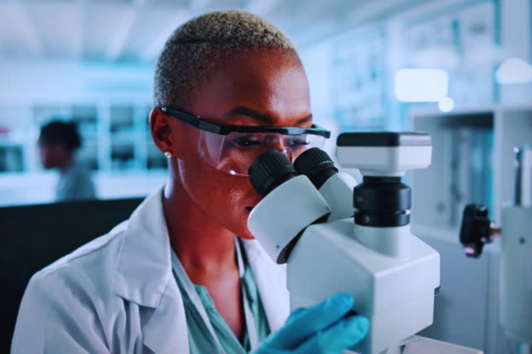 Female scientist using a microscope in a laboratory during test analysis and medical research, illustrating advanced procedures involved in genetic health screening.