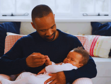 The Science Behind Paternity Testing Accuracy New father cuddling his sleeping baby girl in a home nursery, symbolizing family bonding and the importance of paternity testing accuracy.